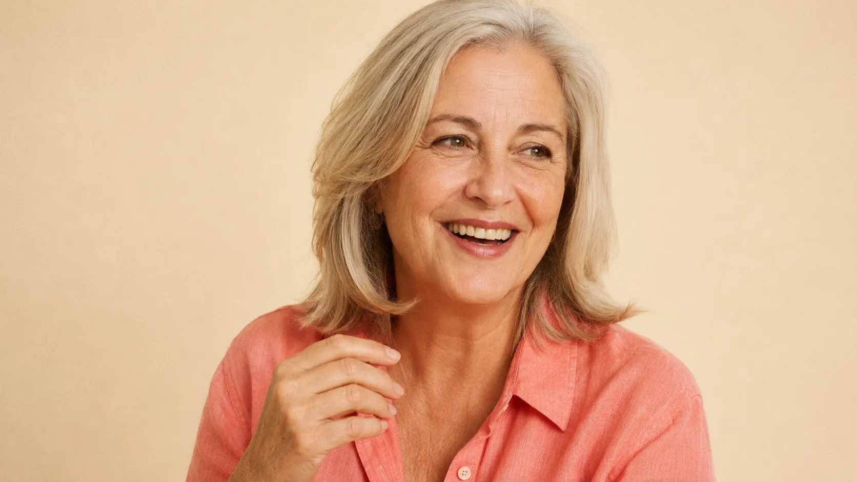 Portrait of Linda — 60-year-old American mother with silver-blonde hair, mid-laugh, coral-pink shirt